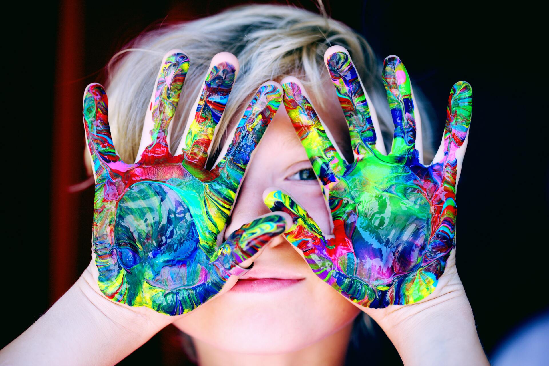 Child with colorful painted hands, excited about art and creativity